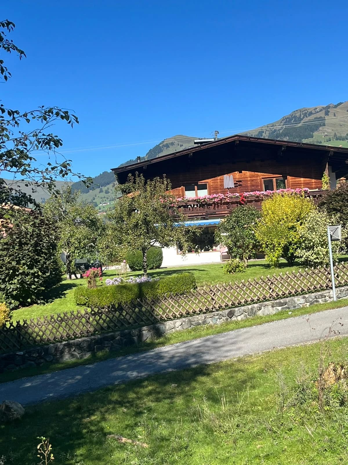 Originalaufnahme des bestehenden Hauses mit blühendem Balkon und gewachsenem Garten